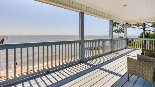Une terrasse en bois avec une rambarde donnant sur une plage.