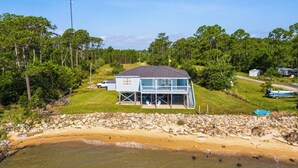 Une maison située en bord de mer, dotée d’un porche couvert et offrant une vue sur l’océan.