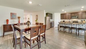 A modern kitchen with wooden cabinets, stainless steel appliances, and a dining area with a wooden table and chairs.