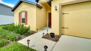 A residential house with a yellow facade, a red door, and a garage.