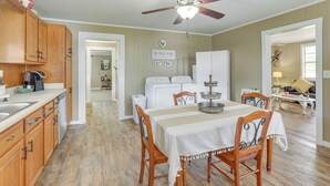 A kitchen with wooden cabinets, a ceiling fan, a dining table with chairs, and a laundry area with appliances.