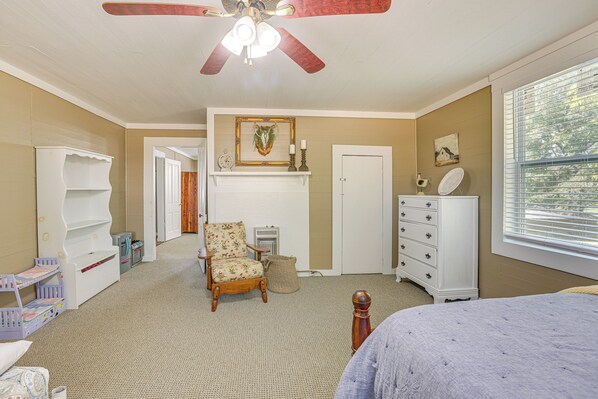 Une chambre à coucher comprenant un lit, une commode, une chaise et un ventilateur de plafond.