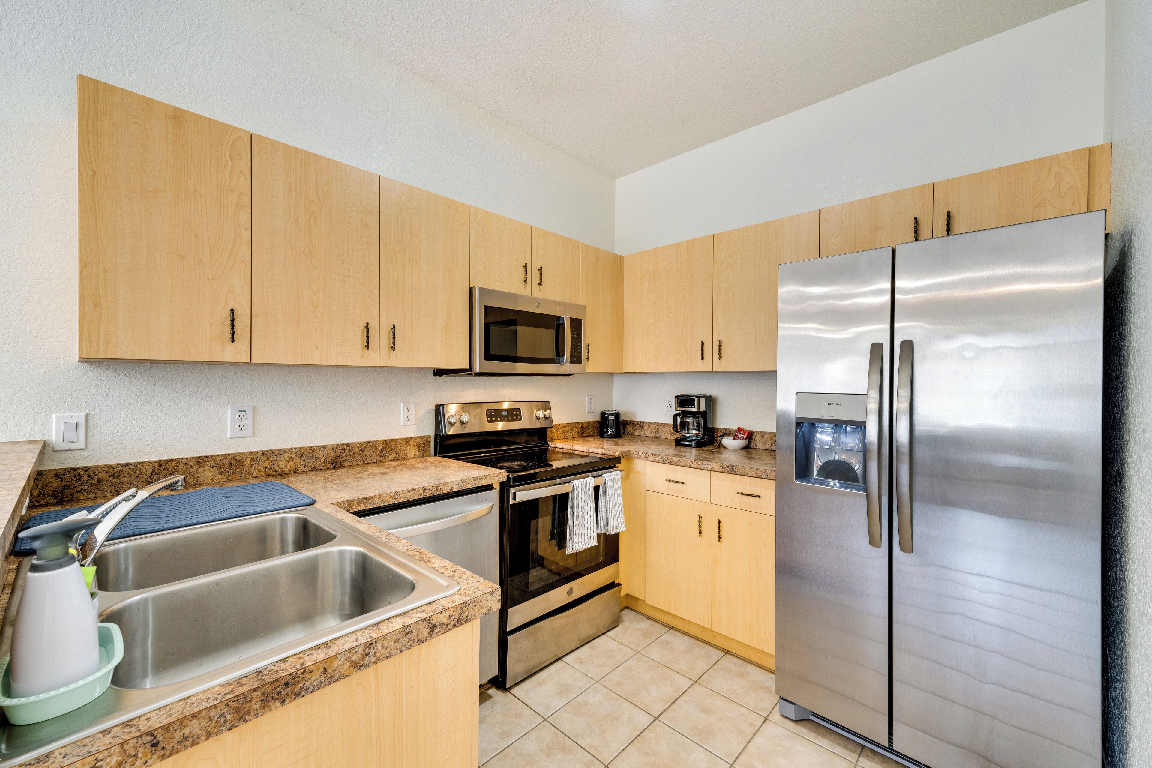 A kitchen with wooden cabinets, stainless steel appliances, a sink, and a granite countertop.