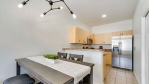Une cuisine moderne dotée d’un îlot central, d’appareils électroménagers en acier inoxydable et d’un coin repas avec une table et des chaises.