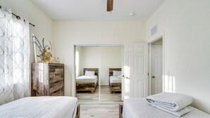 Une chambre avec deux lits, une commode en bois et un miroir.