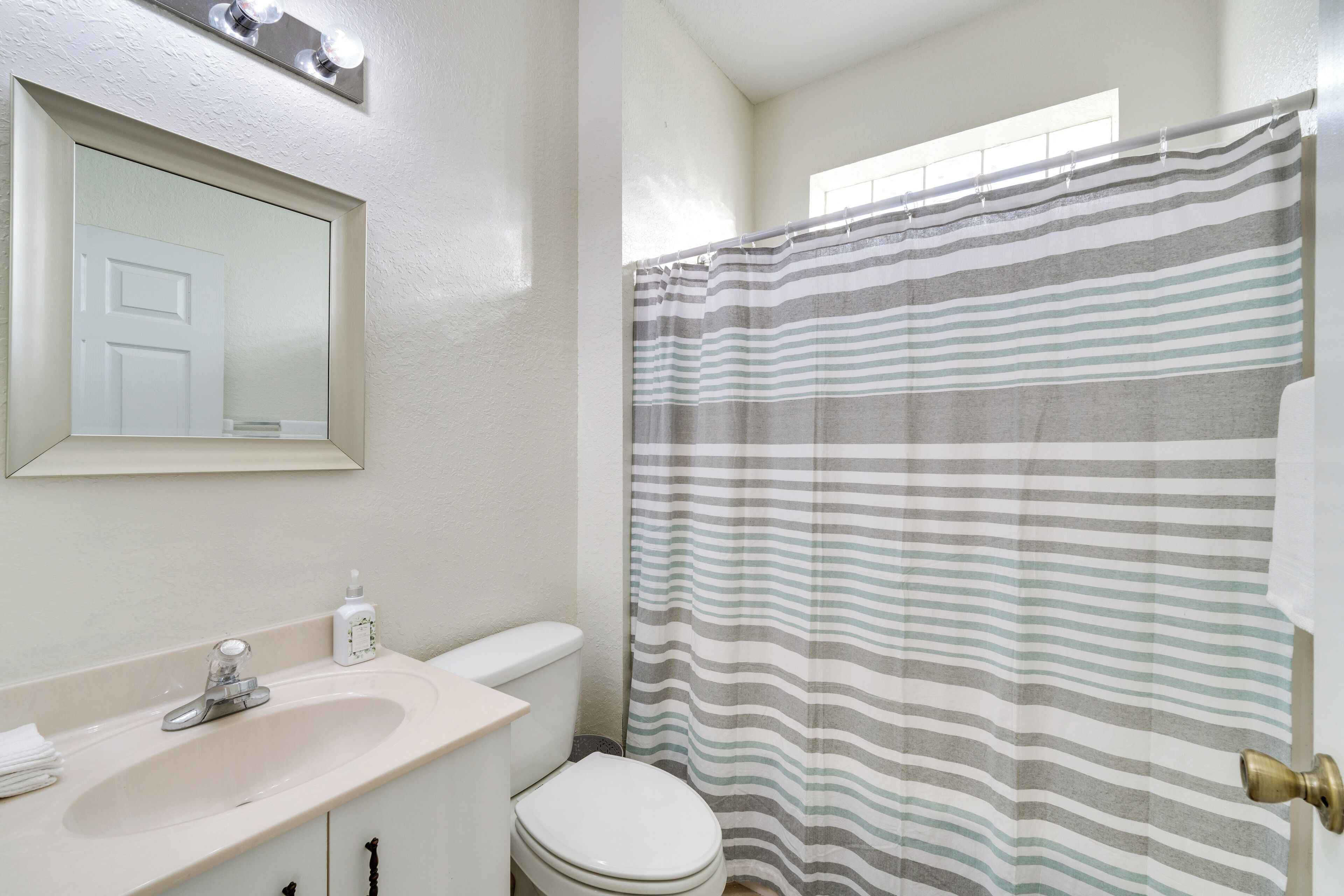 A bathroom with a sink, toilet, and a shower curtain.