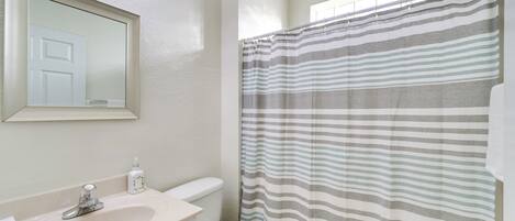 A bathroom with a sink, toilet, and a shower curtain.