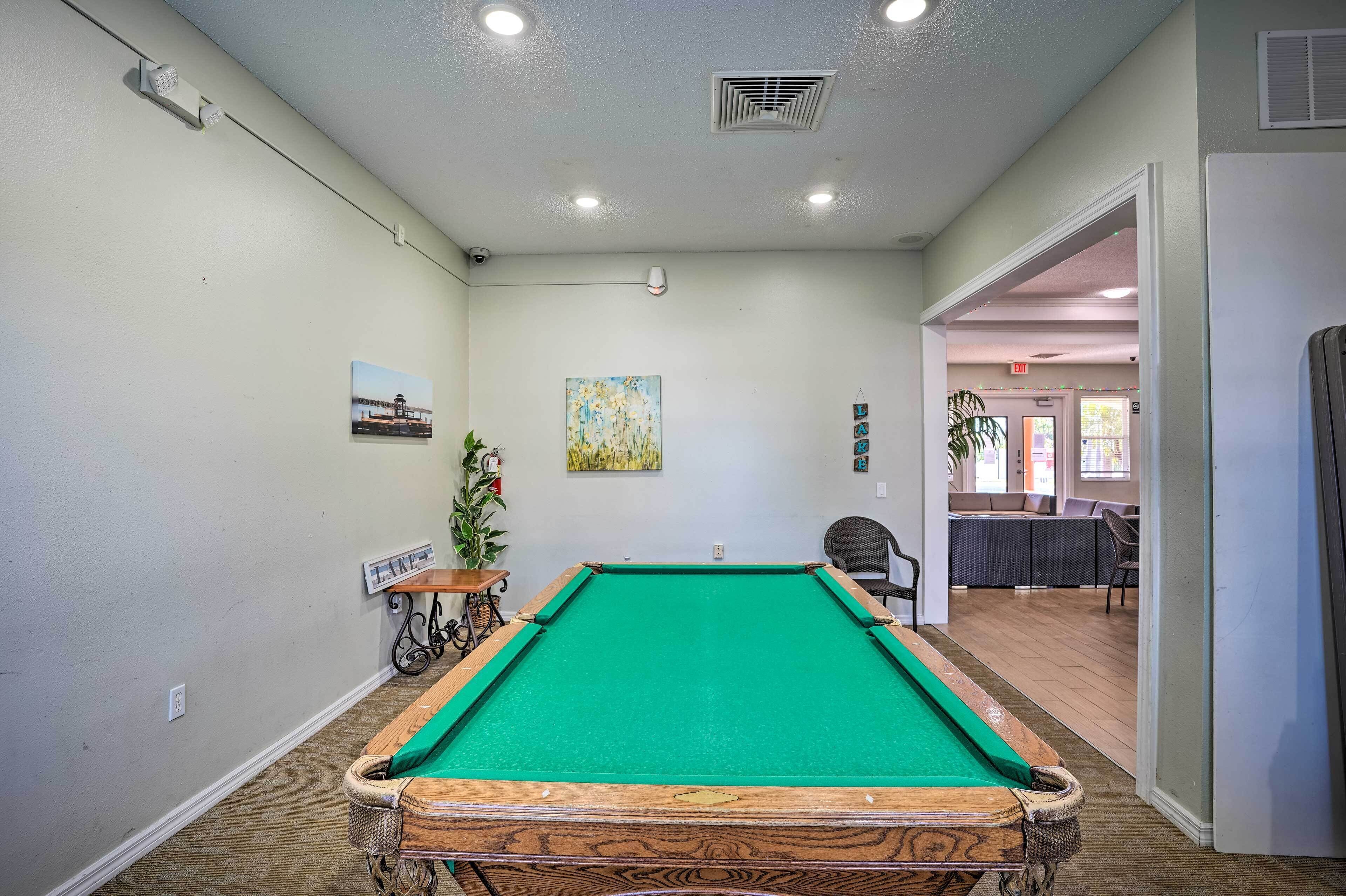 A pool table in a room with a view of a dining area.