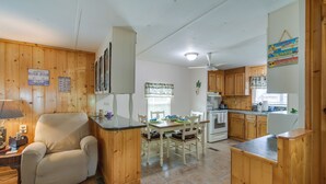 A kitchen with wooden cabinets, a dining table with chairs, a refrigerator, and a stove. - Satsuma Home w/ Fire Pit + Dunns Creek Access! (Satsuma)