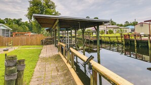 A covered outdoor area with a wooden deck and a pond. - Satsuma Home w/ Fire Pit + Dunns Creek Access! (Satsuma)