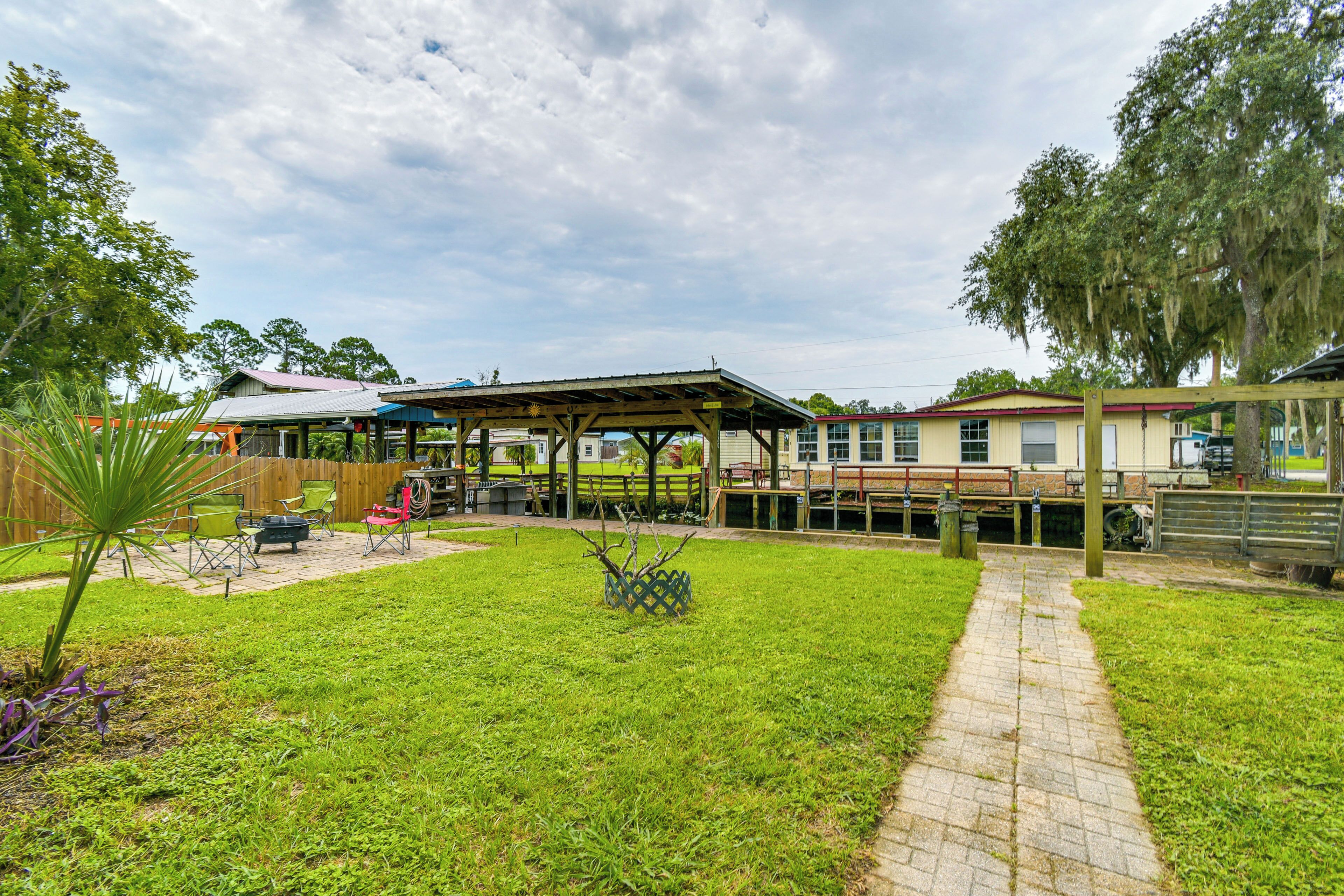 A covered patio area with outdoor seating, a pathway, and a wooden deck.