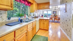A kitchen with wooden cabinets, a sink, and a window with a view of trees. - 40-acre Ararat Escape: On-site Trails & Mtn Views! (Hillsville)