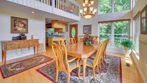 A spacious dining area with a wooden table and chairs, surrounded by patterned rugs, and large windows offering a view of greenery. - 40-acre Ararat Escape: On-site Trails & Mtn Views! (Hillsville)