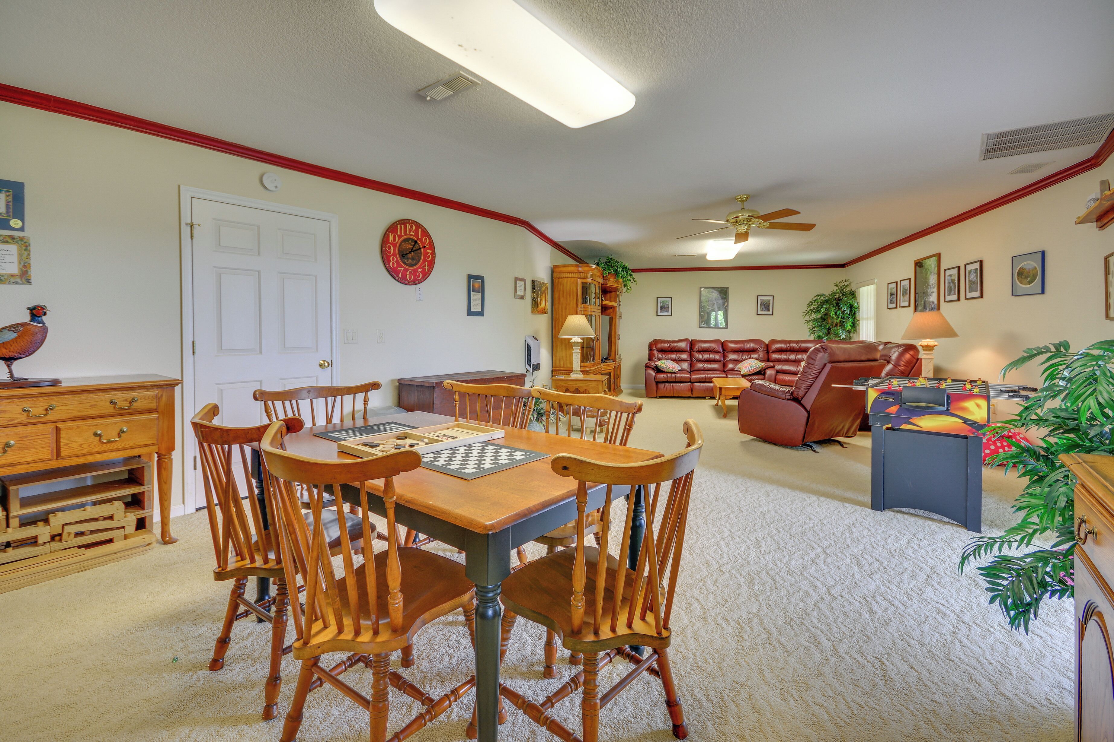 A living room with a wooden dining table, chairs, a sofa, and a foosball table.