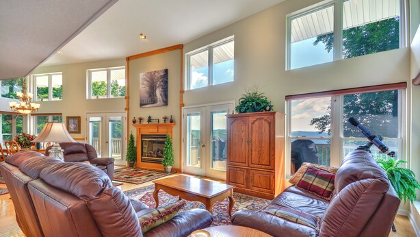A spacious living room with leather sofas, a wooden coffee table, and a fireplace. Large windows provide natural light and views of the outdoors. - 40-acre Ararat Escape: On-site Trails & Mtn Views! (Hillsville)