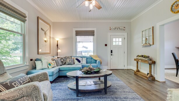 A living room with a sectional sofa, a round coffee table, and a ceiling fan. - Cozy Tennessee Abode w/ Private Hot Tub & Fire Pit (Winchester)