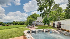 A backyard with a hot tub, a patio with chairs, and a house in the background. - Cozy Tennessee Abode w/ Private Hot Tub & Fire Pit (Winchester)