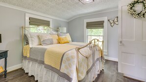 A bedroom with a four-poster bed, a wooden floor, and a white door with a floral wreath. - Cozy Tennessee Abode w/ Private Hot Tub & Fire Pit (Winchester)