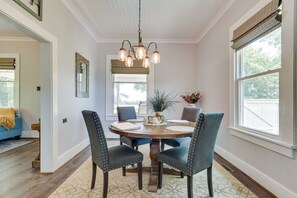 Enjoy meals in this inviting dining area with a round table and comfortable chairs, surrounded by a large window and a beautiful potted plant.