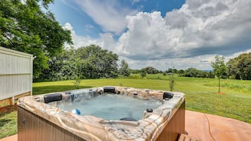 Relax in a hot tub surrounded by a deck and lush greenery.
