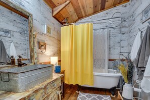 Bathroom features a large sink, bathtub, and wooden vanity with a mirror.