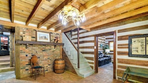 A rustic interior with a wooden staircase, brick walls, and a chandelier. - Glasgow Getaway w/ Patio, Fireplace & Grill! (Glasgow)