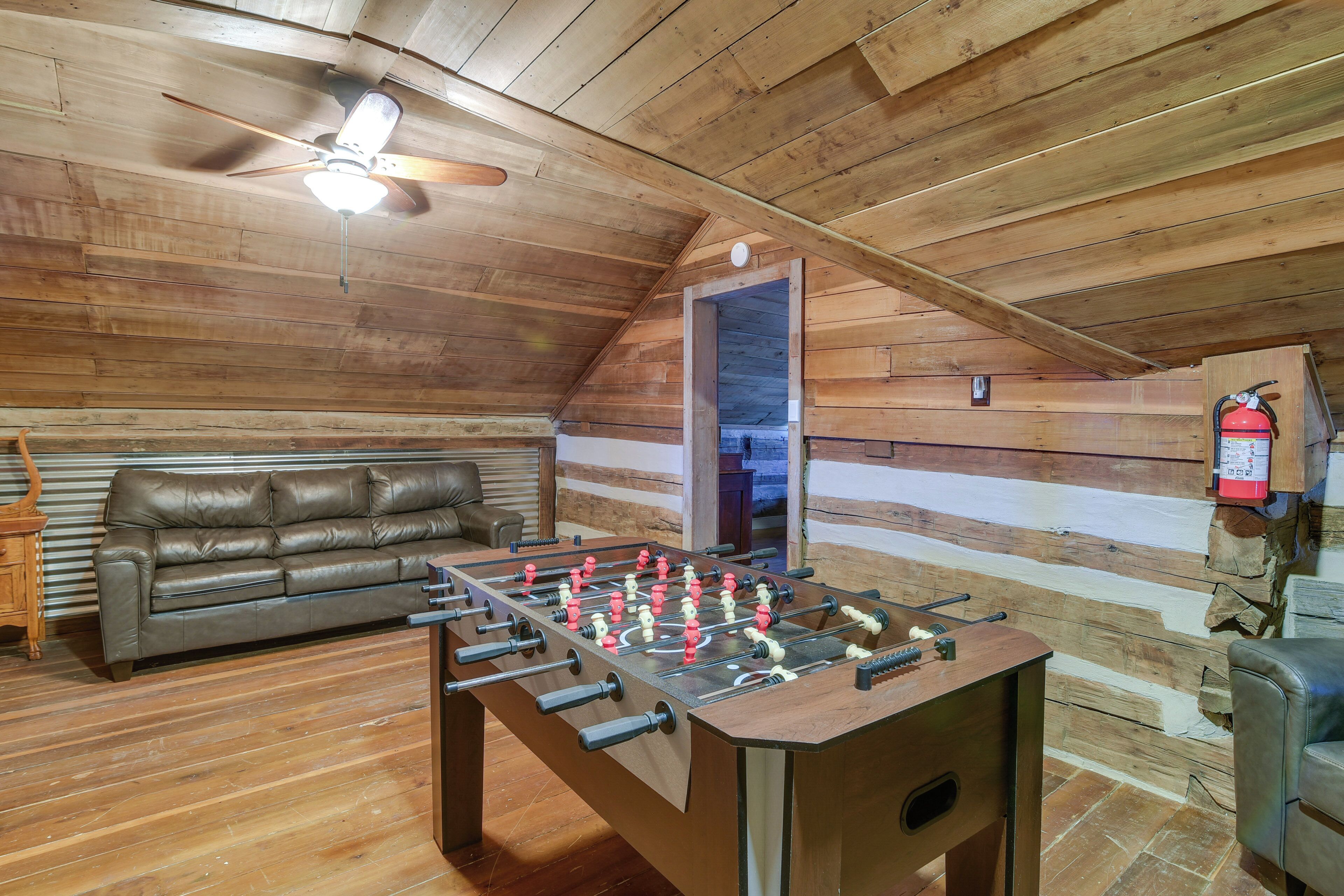 A cozy room with a foosball table, a leather sofa, and a ceiling fan.