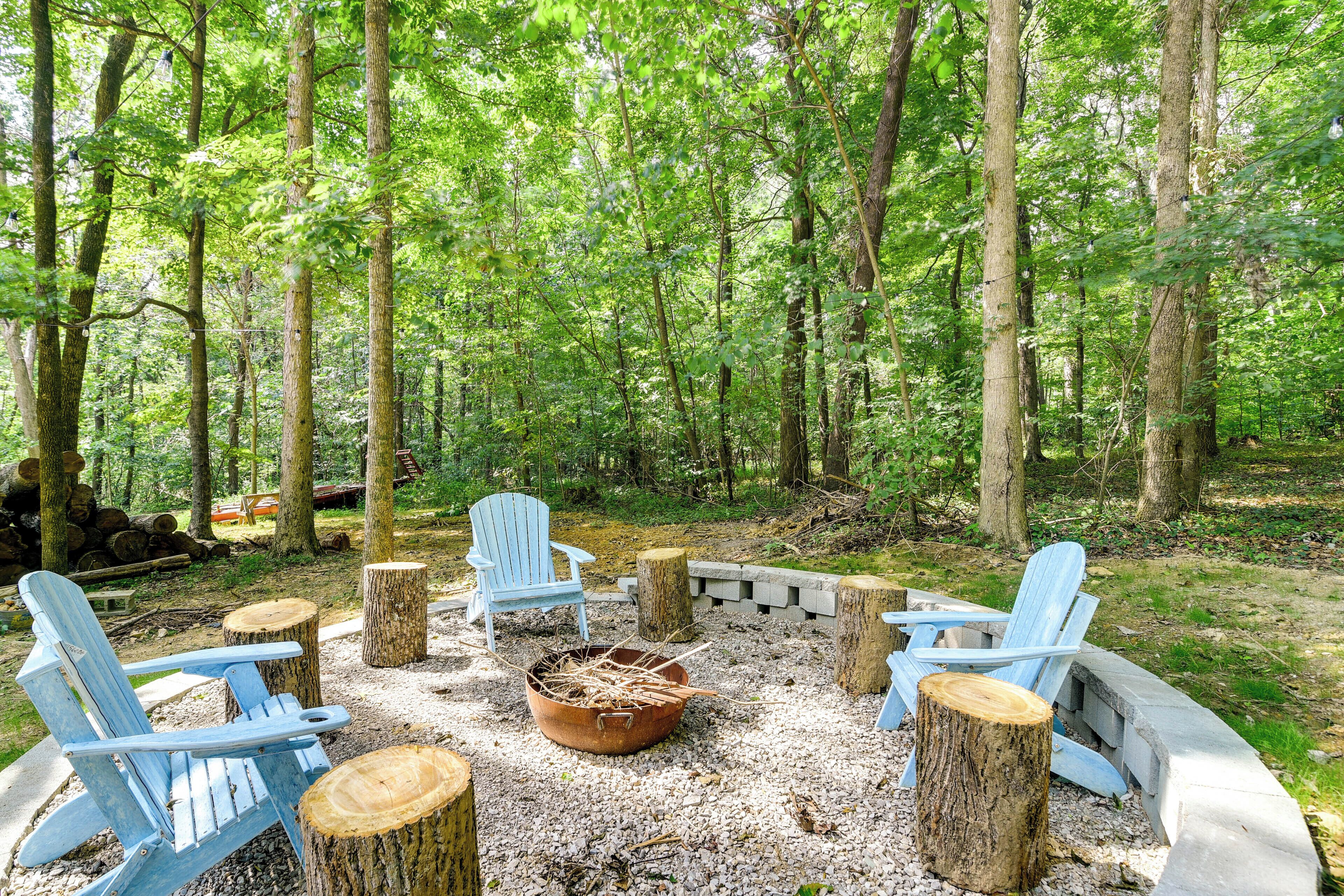 Ein bewaldetes Gebiet mit Adirondack-Stühlen, die um eine Feuerstelle angeordnet sind.