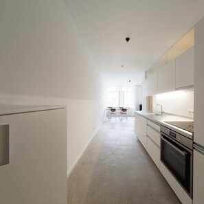 Een moderne keuken met witte kasten, een centraal eiland en een eetgedeelte met stoelen.