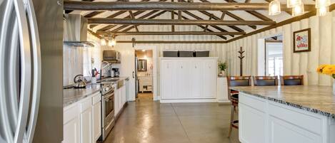 A spacious kitchen with a large island, wooden beams on the ceiling, and a view into the dining area.