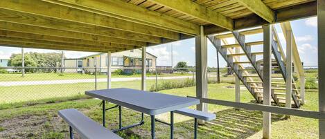 Ein überdachter Picknickbereich im Freien mit Tisch und Bänken, Holzbalken und einer Treppe.