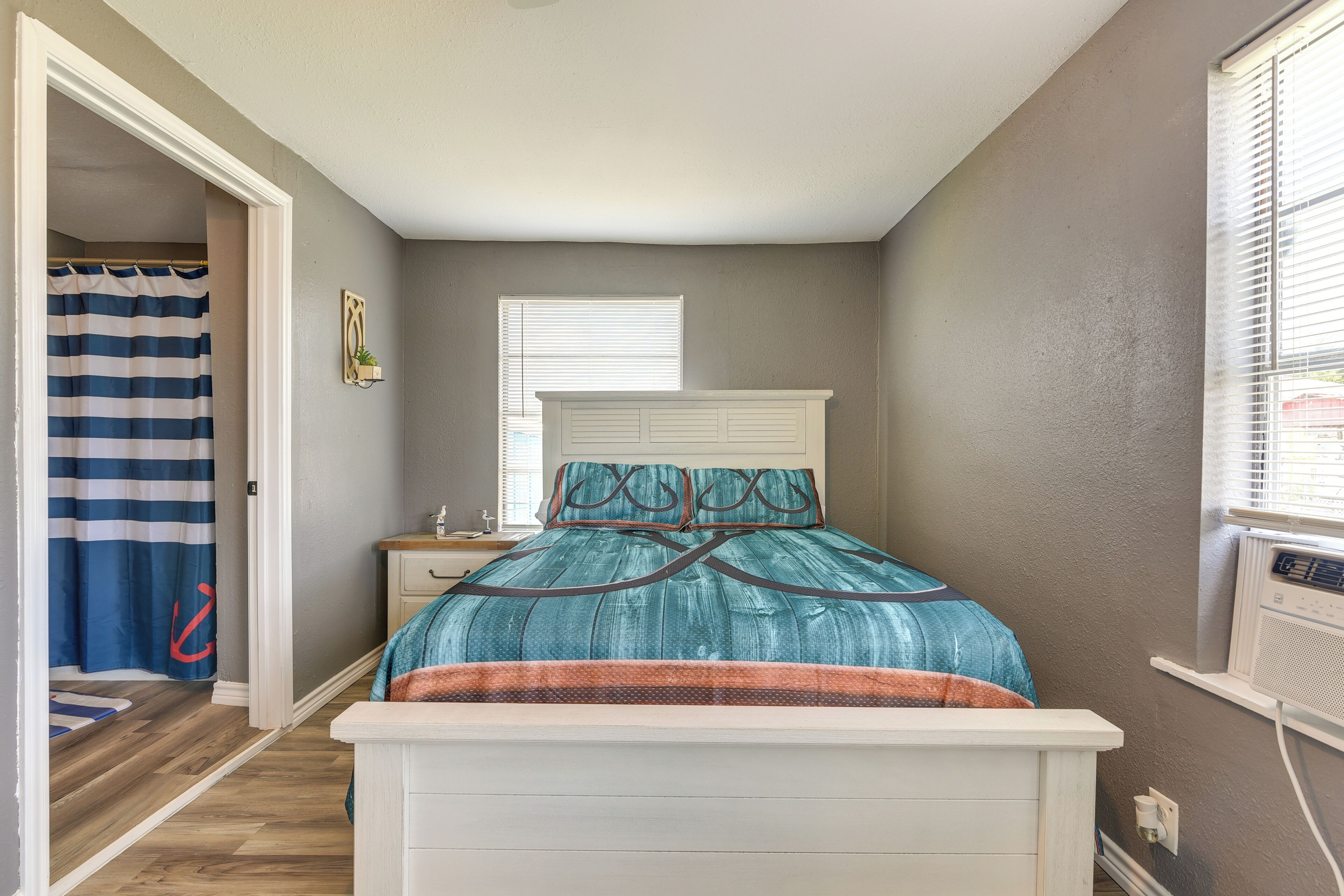 Un dormitorio con cama, mesita de noche, ventana y cortina de ducha.