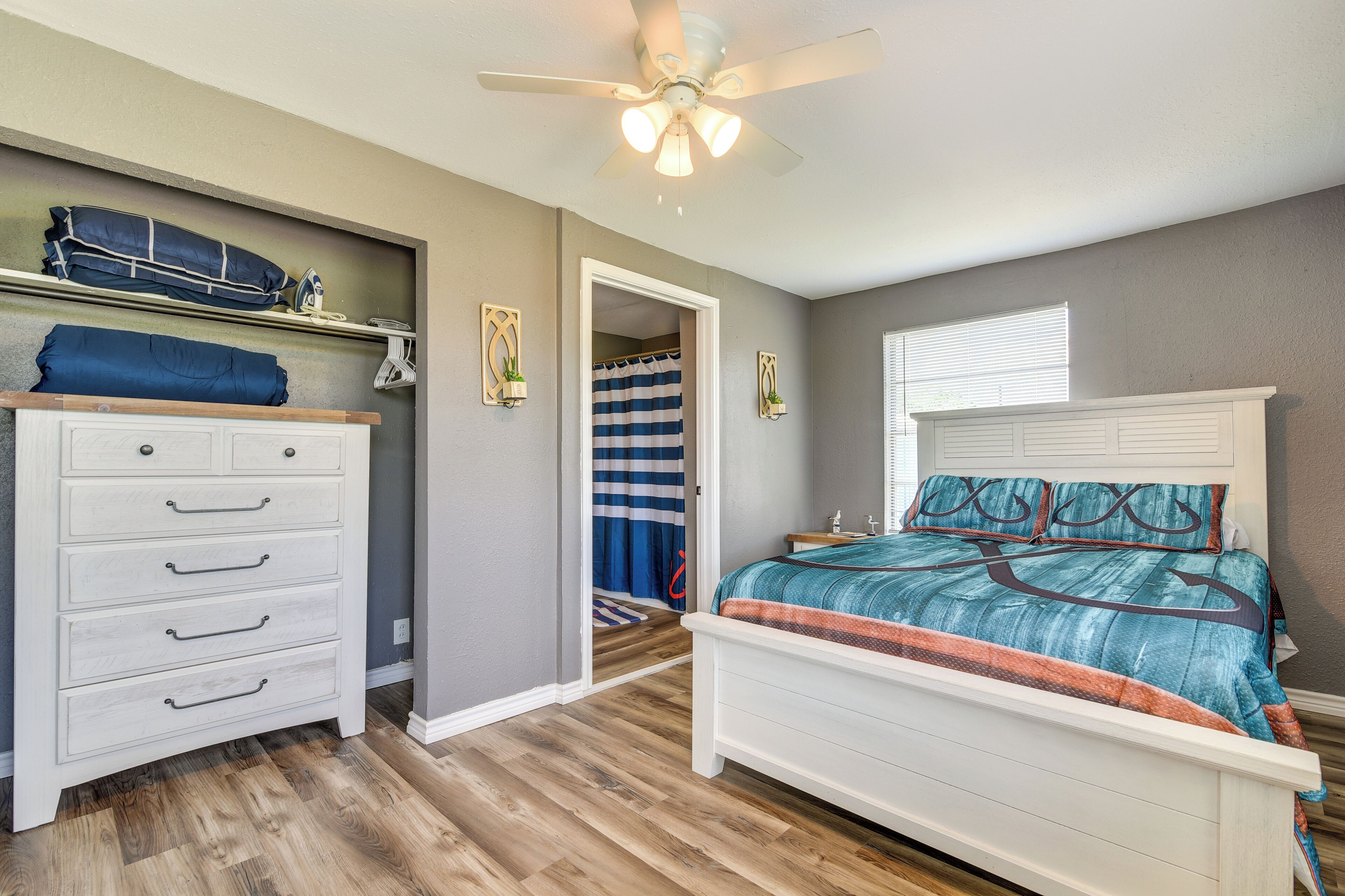 Een slaapkamer met een bed, een dressoir, een plafondventilator en een douche.