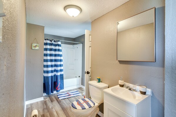 A bathroom with a toilet, sink, and shower curtain. - Deck & Fenced-in Yard: Texas Escape! (Freeport)