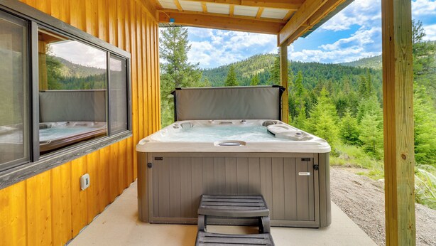 A hot tub in a wooden cabin with a view of a forested mountain. - Modern Lakeside Cabin w/ Mountain Views & Hot Tub! (Lakeside)