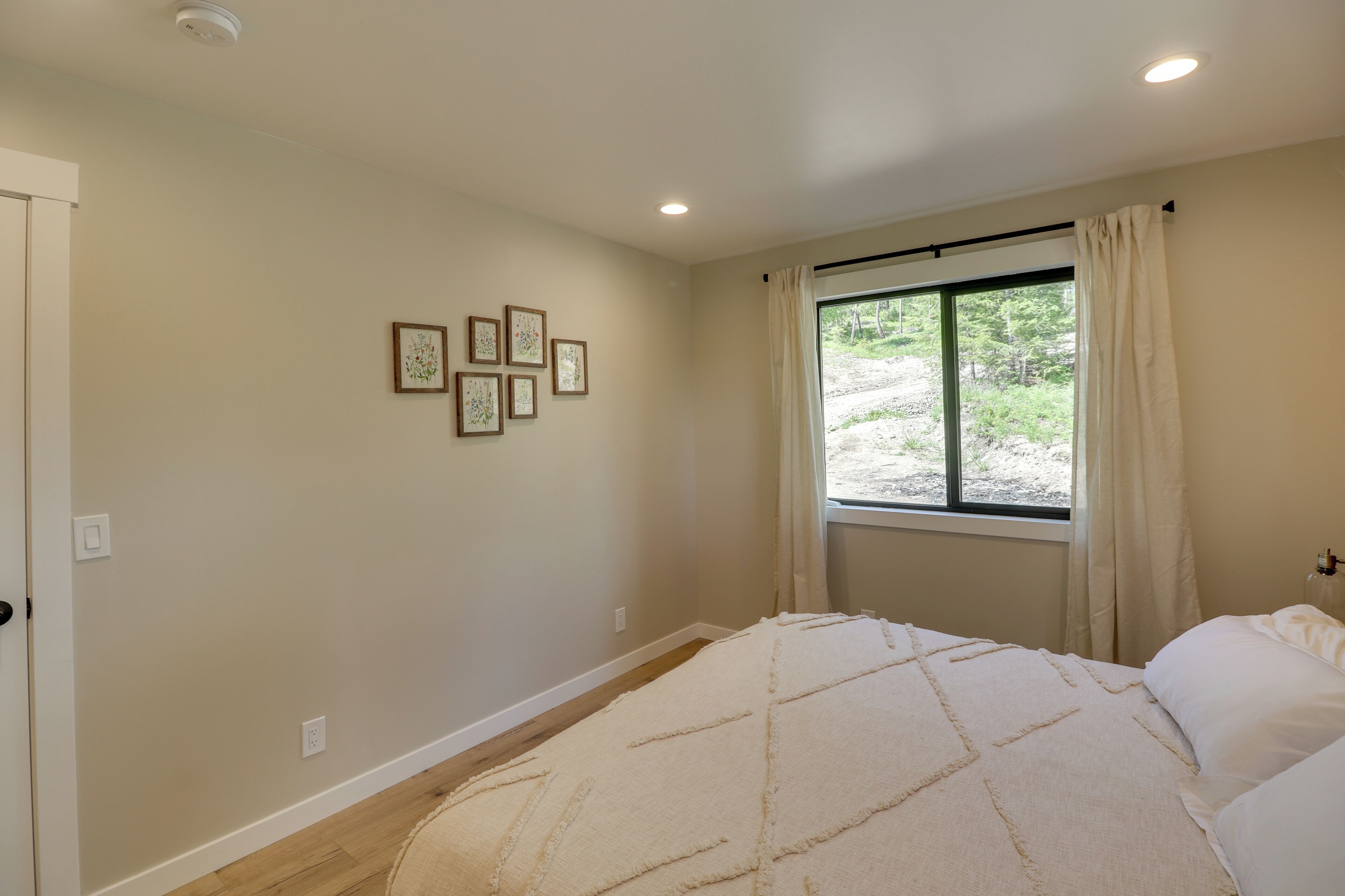A bedroom with a bed, a window with curtains, and wall-mounted pictures.