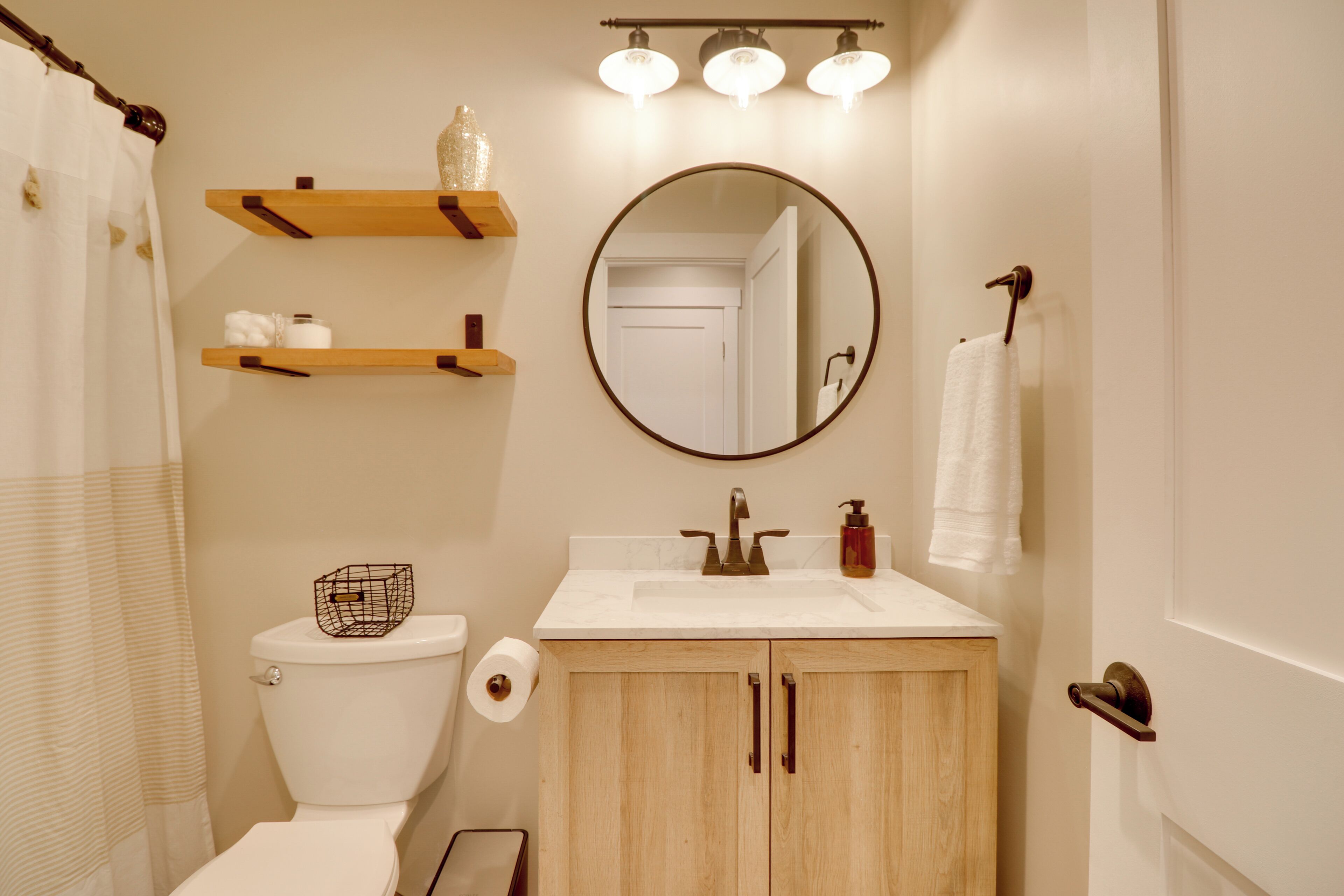 A bathroom with a toilet, sink, mirror, and towel rack.