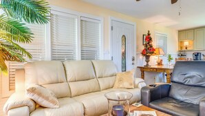 Ein Wohnzimmer mit einem beigen Sofa, einem schwarzen Ledersessel, einem Couchtisch mit Dekoration und einem Weihnachtsbaum.