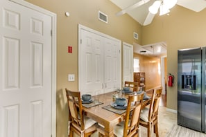 A dining area with a wooden table set for six, surrounded by chairs. There are white double doors and a stainless steel refrigerator to the right. - Keansburg Home w/ Private Hot Tub! (Keansburg)