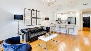 A modern living room with a black leather sofa, a white coffee table, and a black floor lamp. - Fayetteville Vacation Rental Near UA Campus (Fayetteville)