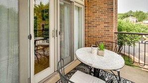 A balcony with a glass door, a round table with a potted plant, and a patterned rug. - Fayetteville Vacation Rental Near UA Campus (Fayetteville)