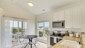 A modern kitchen with white cabinets, a granite countertop, a built-in microwave, and a large window. - Inviting Atlantic Beach Townhome ~ 1/2 Mi to Ocean (Atlantic Beach)