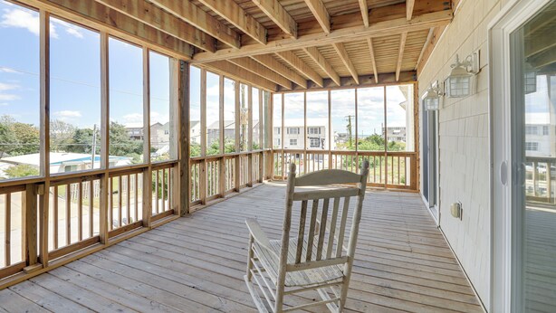 A wooden deck with a rocking chair, large windows, and a view of the neighborhood. - Inviting Atlantic Beach Townhome ~ 1/2 Mi to Ocean (Atlantic Beach)