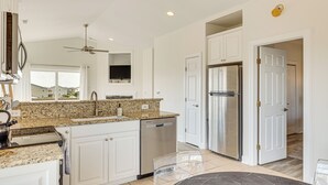 A modern kitchen with white cabinetry, granite countertops, a dishwasher, a refrigerator, and a ceiling fan. - Inviting Atlantic Beach Townhome ~ 1/2 Mi to Ocean (Atlantic Beach)