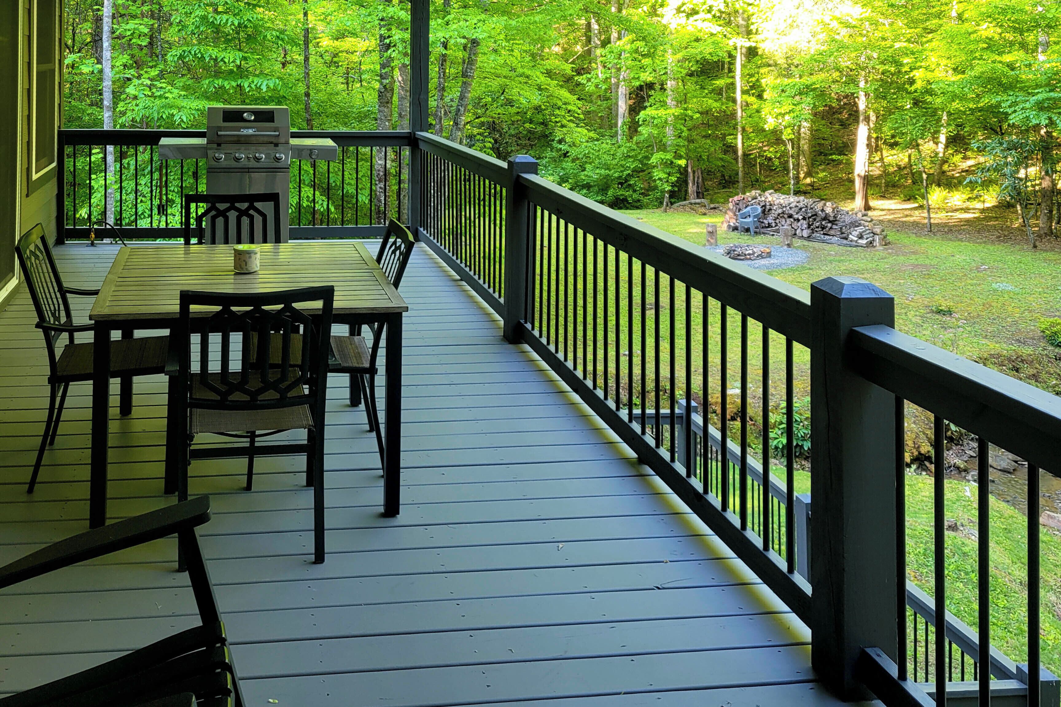 A wooden deck with a grill, chairs, and a table.