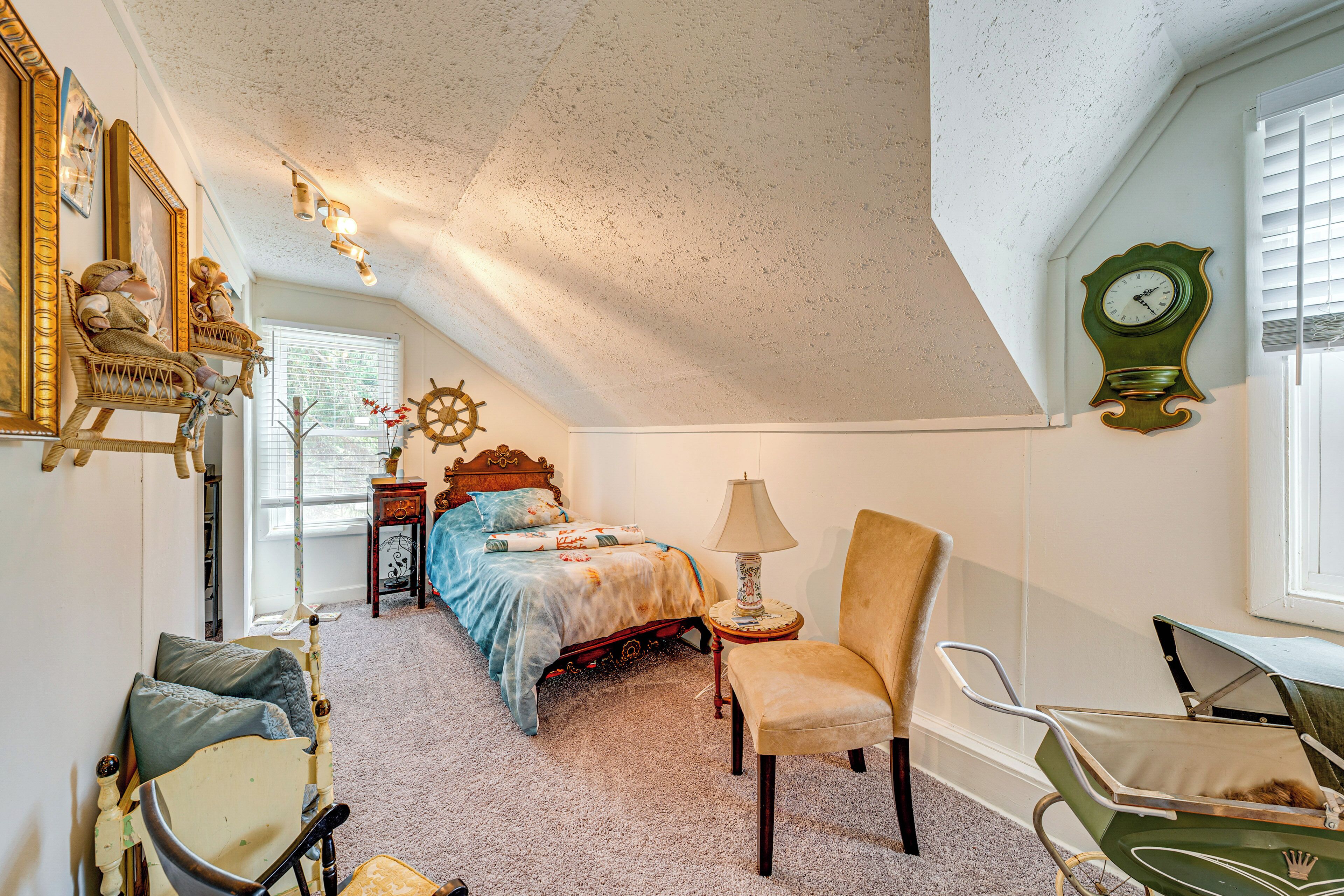 A bedroom with a bed, a chair, a lamp, a clock, and a window.