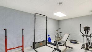 Un gimnasio con barra de dominadas, bicicleta estática, banco y banco de pesas.