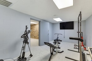 Ett gym med träningsutrustning, en tv och en tegelvägg.