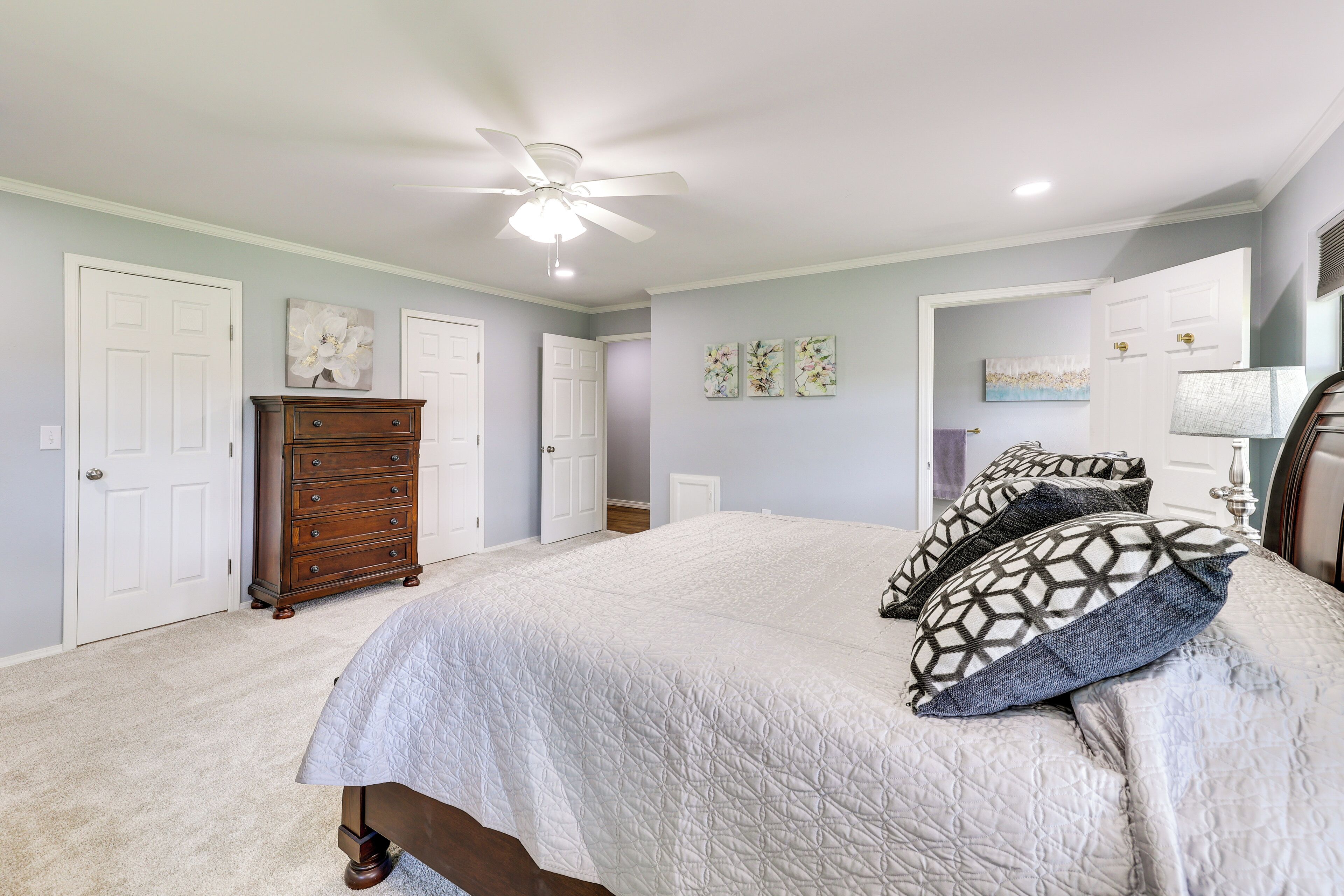 A bedroom with a bed, dresser, and ceiling fan.