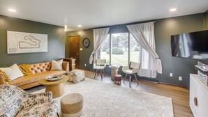 Een woonkamer met een bank, stoelen, een salontafel, een vloerkleed en een televisie.